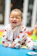 A joyful baby wearing a colorful onesie, playing with a plush toy in a bright nursery.