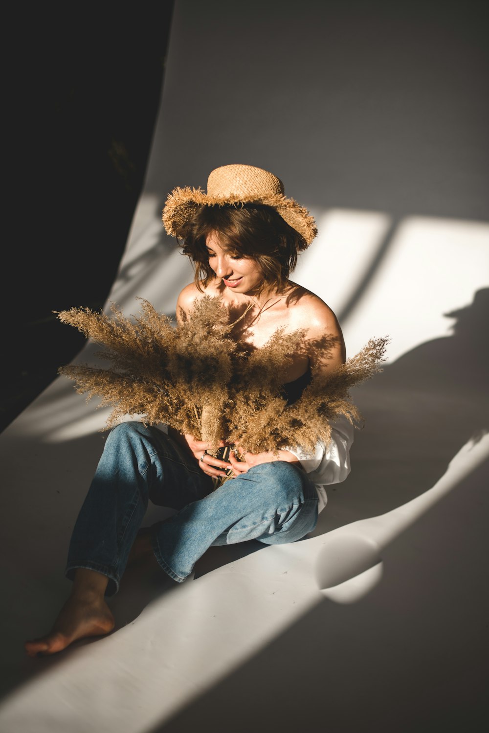 woman in blue denim jeans wearing brown sun hat sitting on white chair