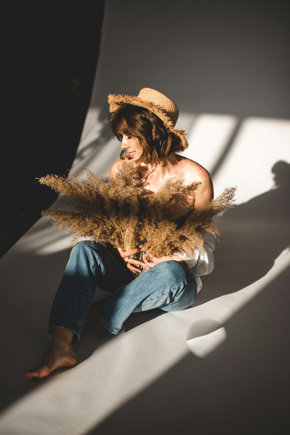 woman in blue denim jeans and brown hat sitting on white chair