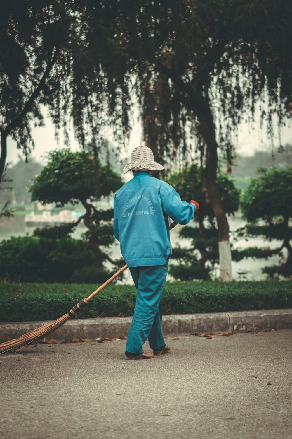homme en veste bleue et pantalon gris tenant un bâton marchant sur le sentier