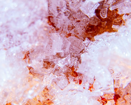 A close-up view of crystalline structures with intricate details. The crystalline shapes are varied, with sharp edges and some transparency, creating a textured and layered visual effect.