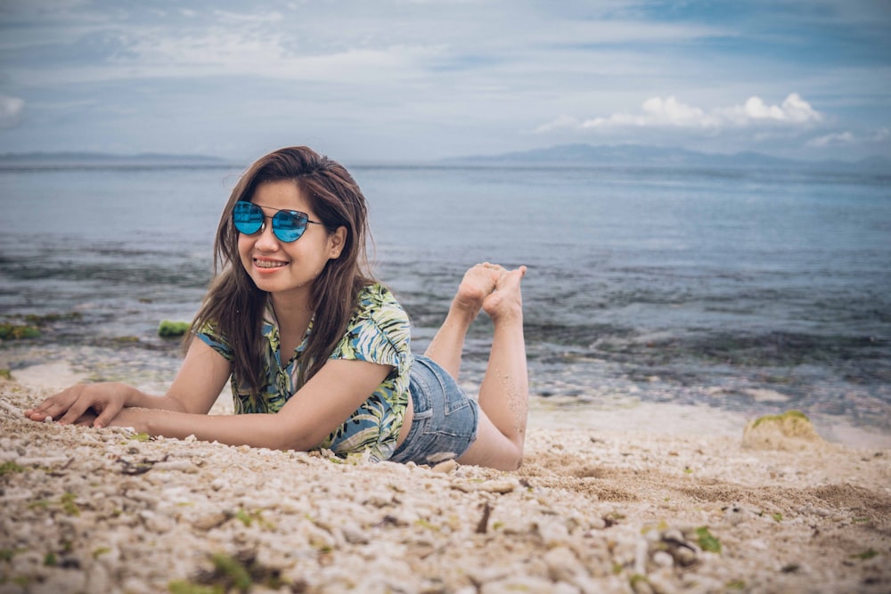 woman in green and white stripe shirt lying on brown sand during daytime