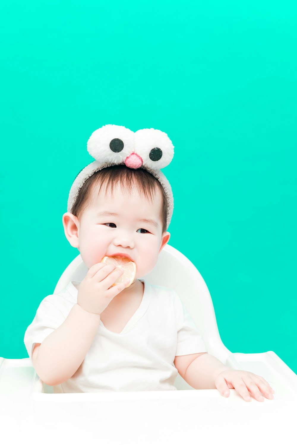 baby in white long sleeve shirt and white and black polka dot headband