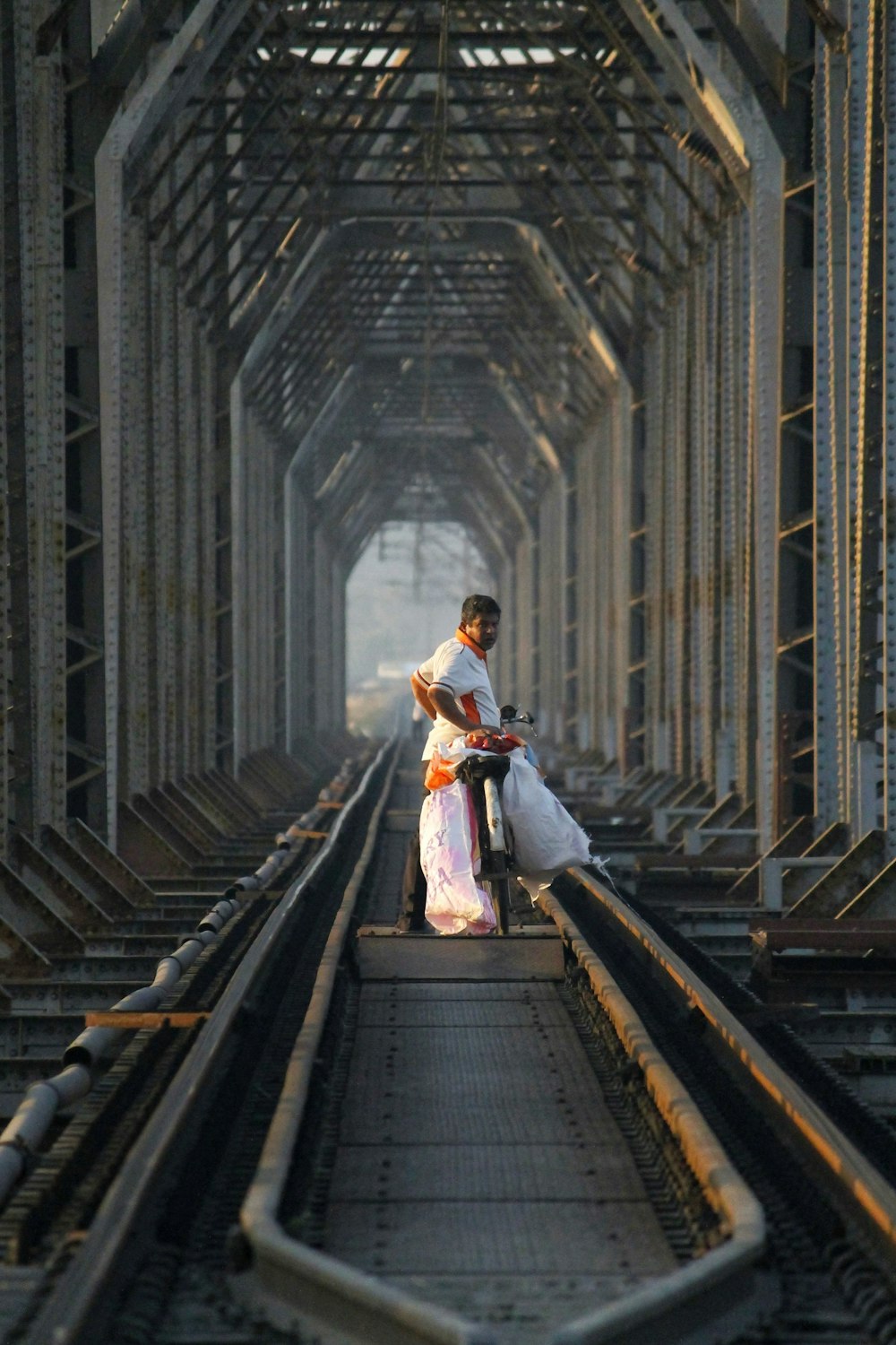 woman in white dress sitting on brown wooden bridge