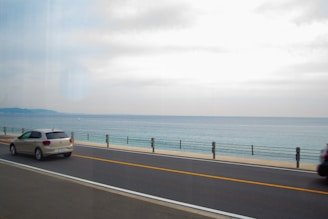A sunny coastal road in Mayotte with a rental car driving along the lagoon.