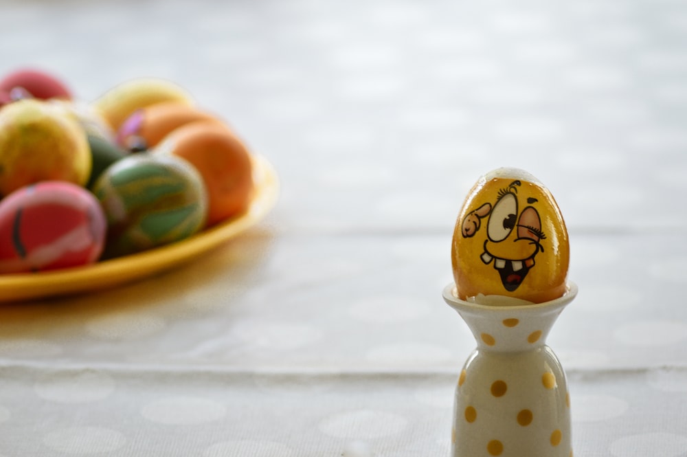 an egg with a face painted on it next to a plate of eggs