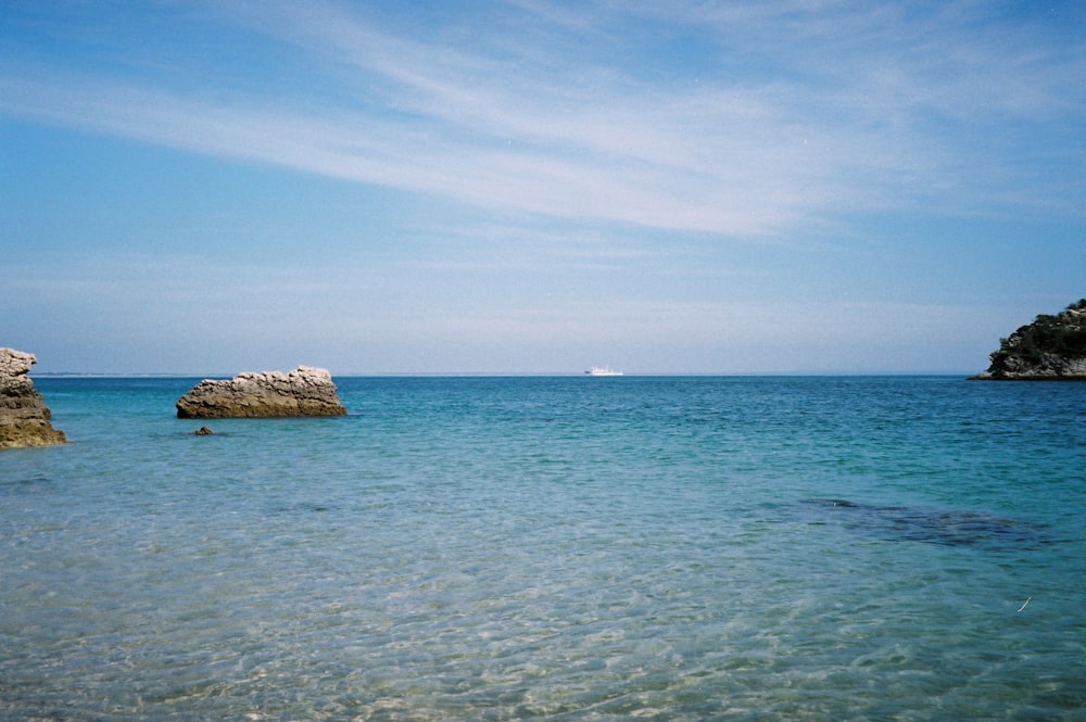 brown rock formation on sea under blue sky during daytime