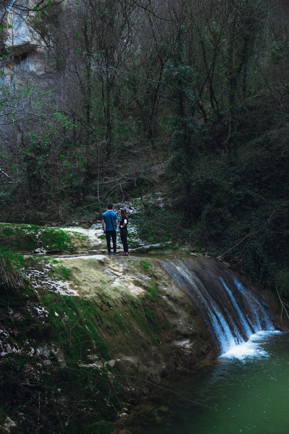 Mann in rotem Hemd und schwarzen Shorts geht auf dem Fluss