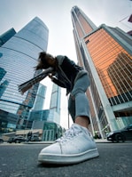 woman in green jacket and white denim jeans standing on sidewalk during daytime