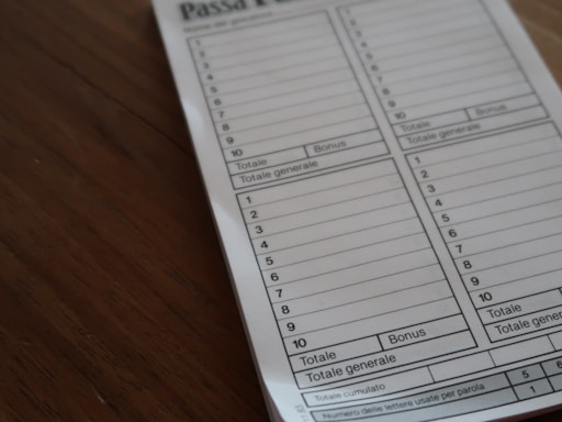 A close-up view of a game score sheet labeled 'Passa Parola'. The sheet is divided into columns with numbered rows for recording scores, marked with 'Totale' and 'Bonus'. It is placed on a wooden surface.