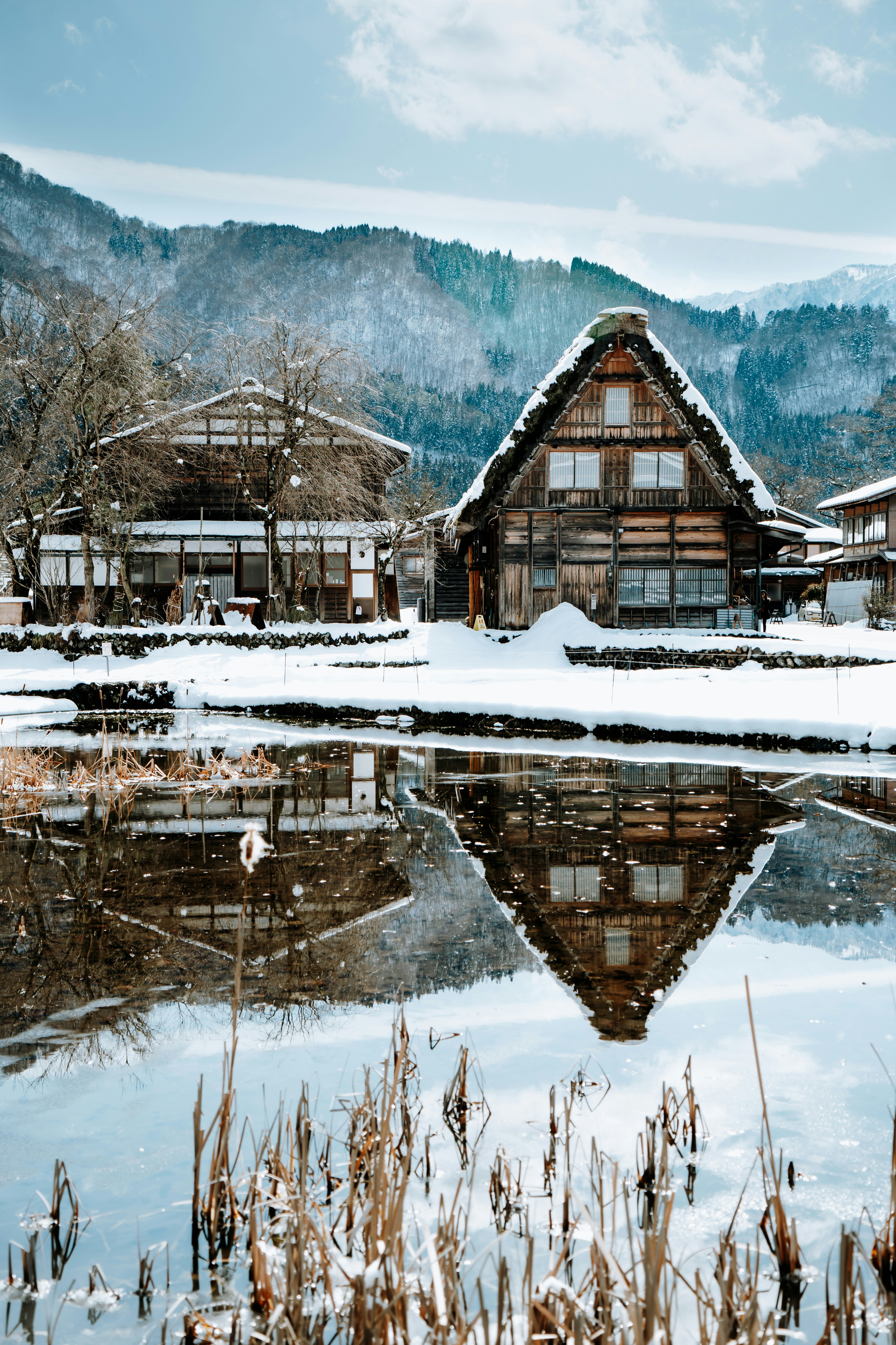brown wooden house on snow covered ground near body of water during daytime
