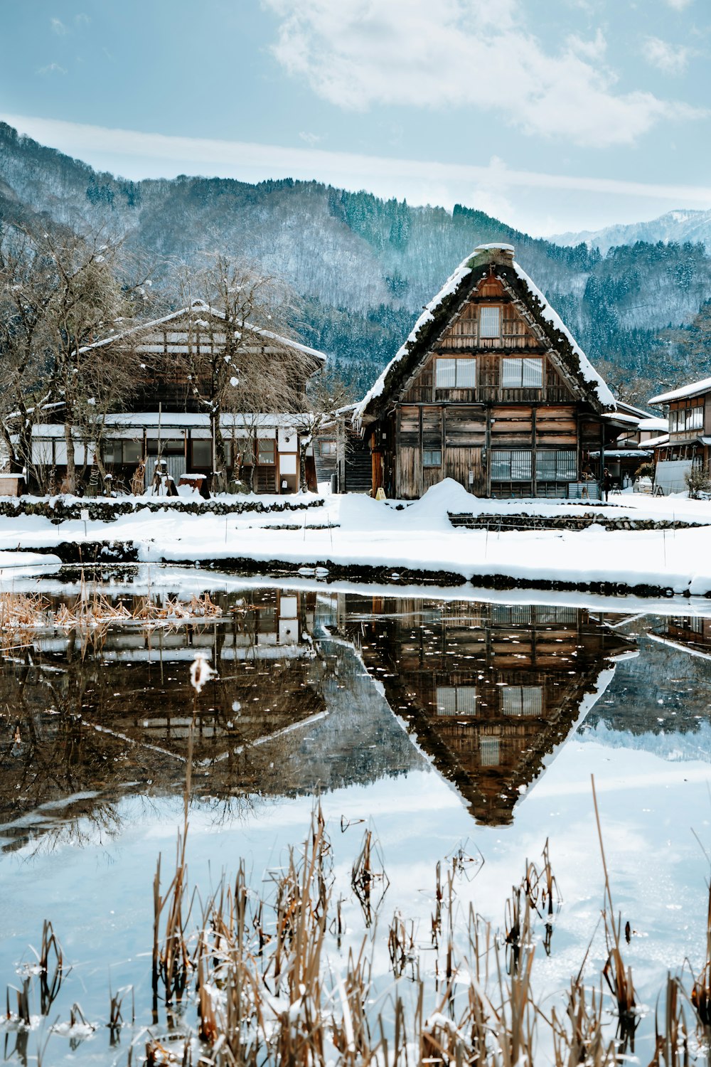 brown wooden house on snow covered ground near body of water during daytime