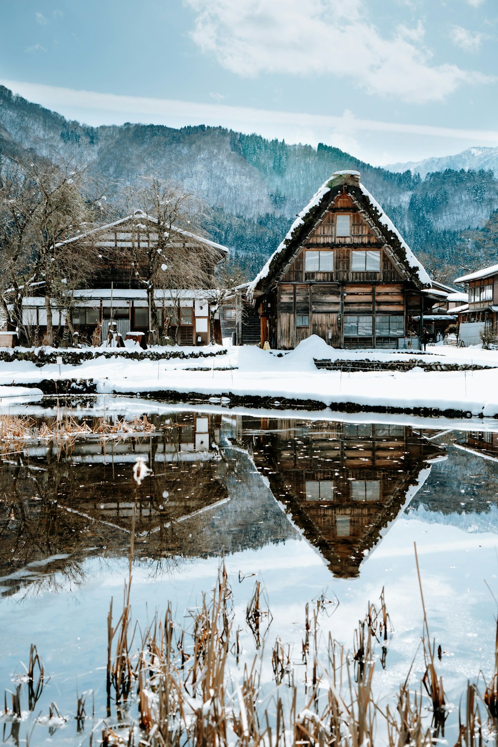 Braunes Holzhaus auf schneebedecktem Boden in der Nähe von Gewässern tagsüber