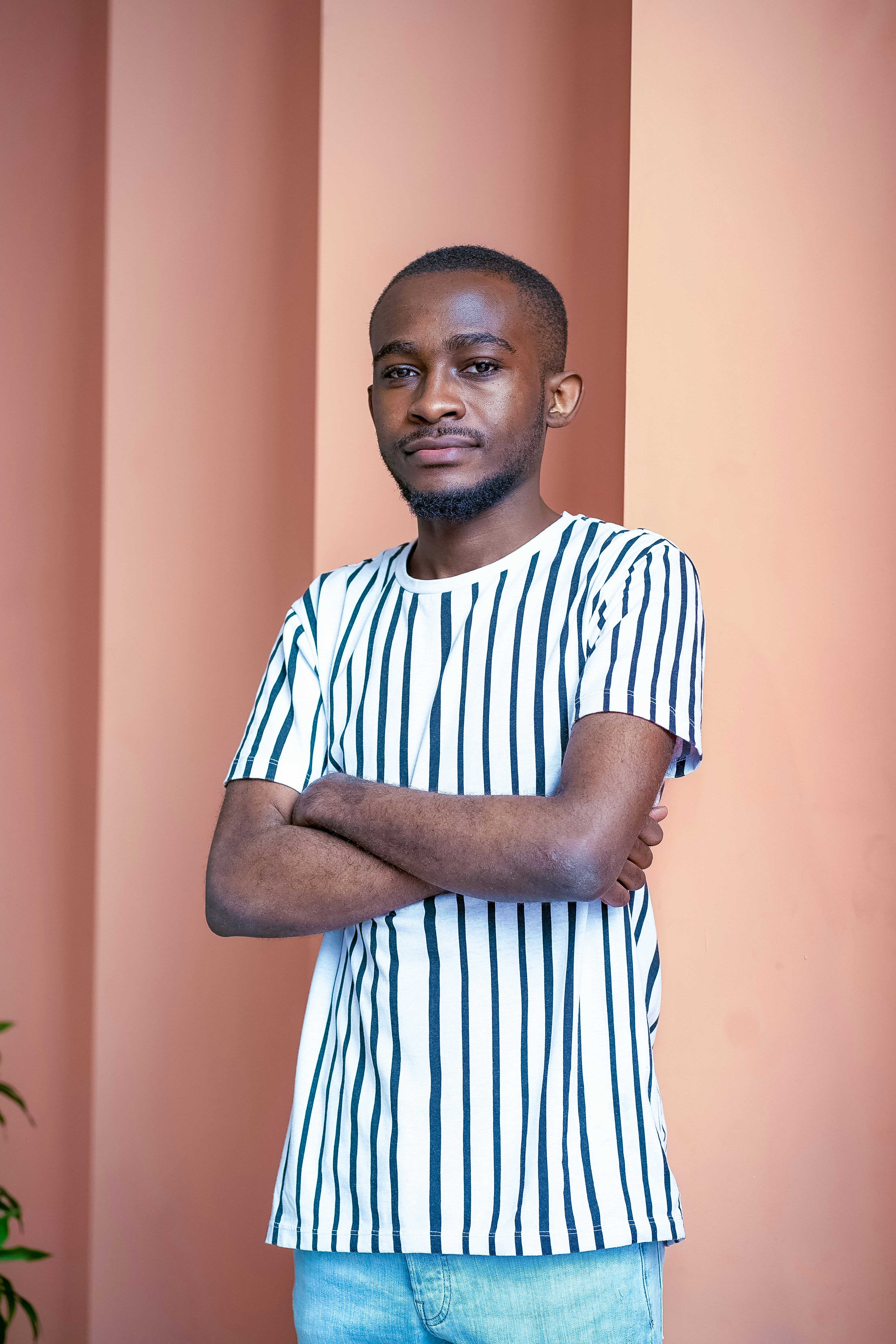 man in white and blue striped crew neck t-shirt standing near orange wall