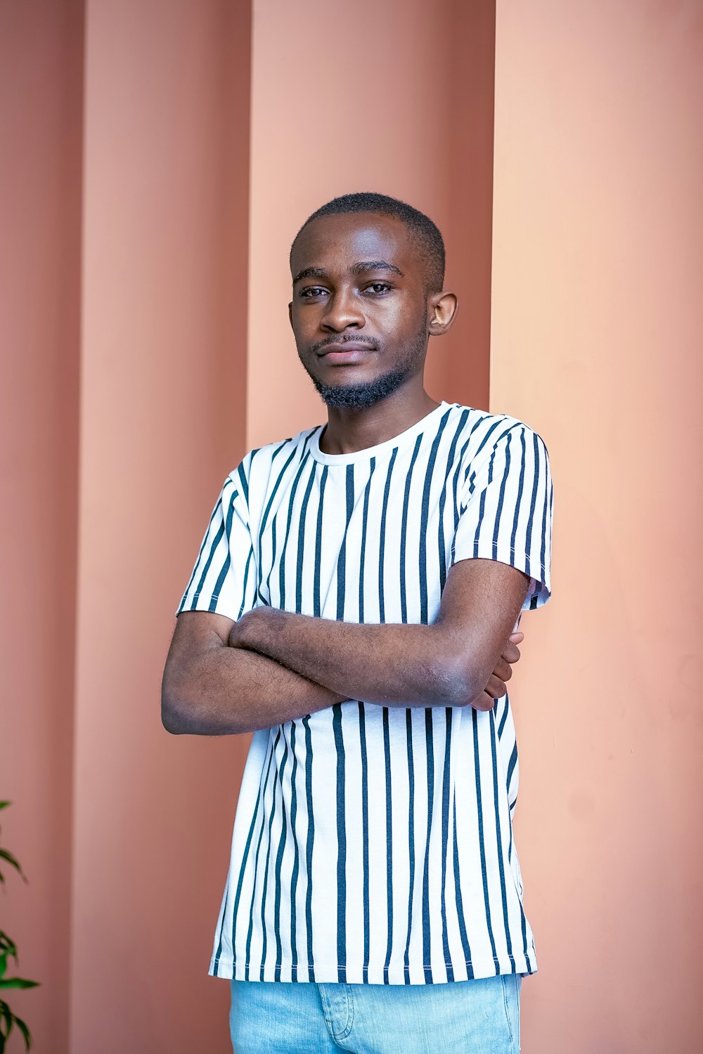 man in white and blue striped crew neck t-shirt standing near orange wall