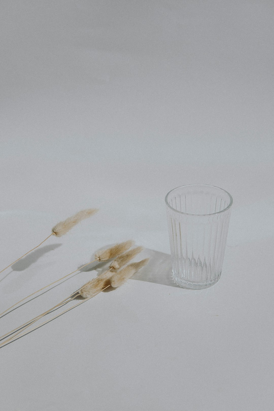 clear drinking glass beside white plastic spoon