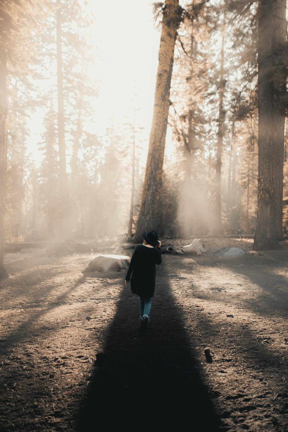 woman in black jacket walking on dirt road during daytime