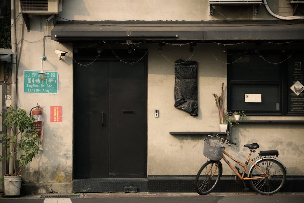 bicicletta nera parcheggiata accanto alla porta di legno nera