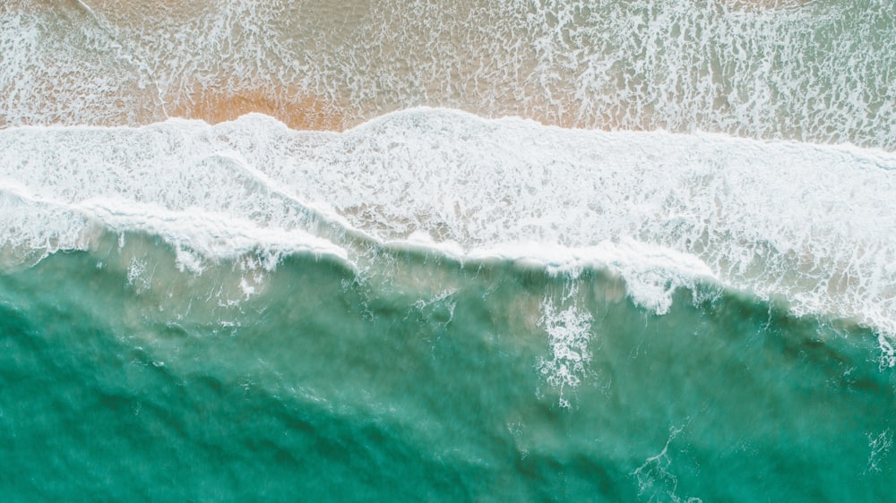 areia marrom ao lado do corpo de água durante o dia