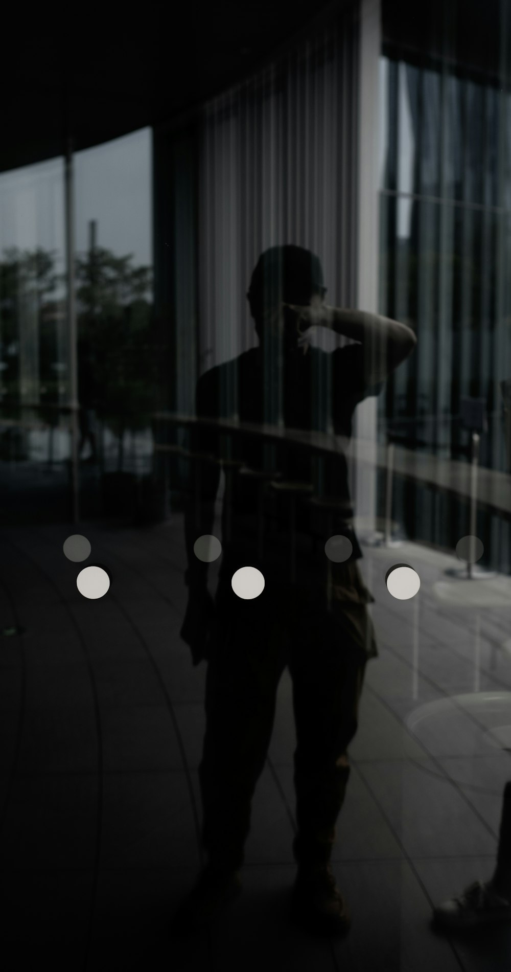 man in black pants standing near glass window