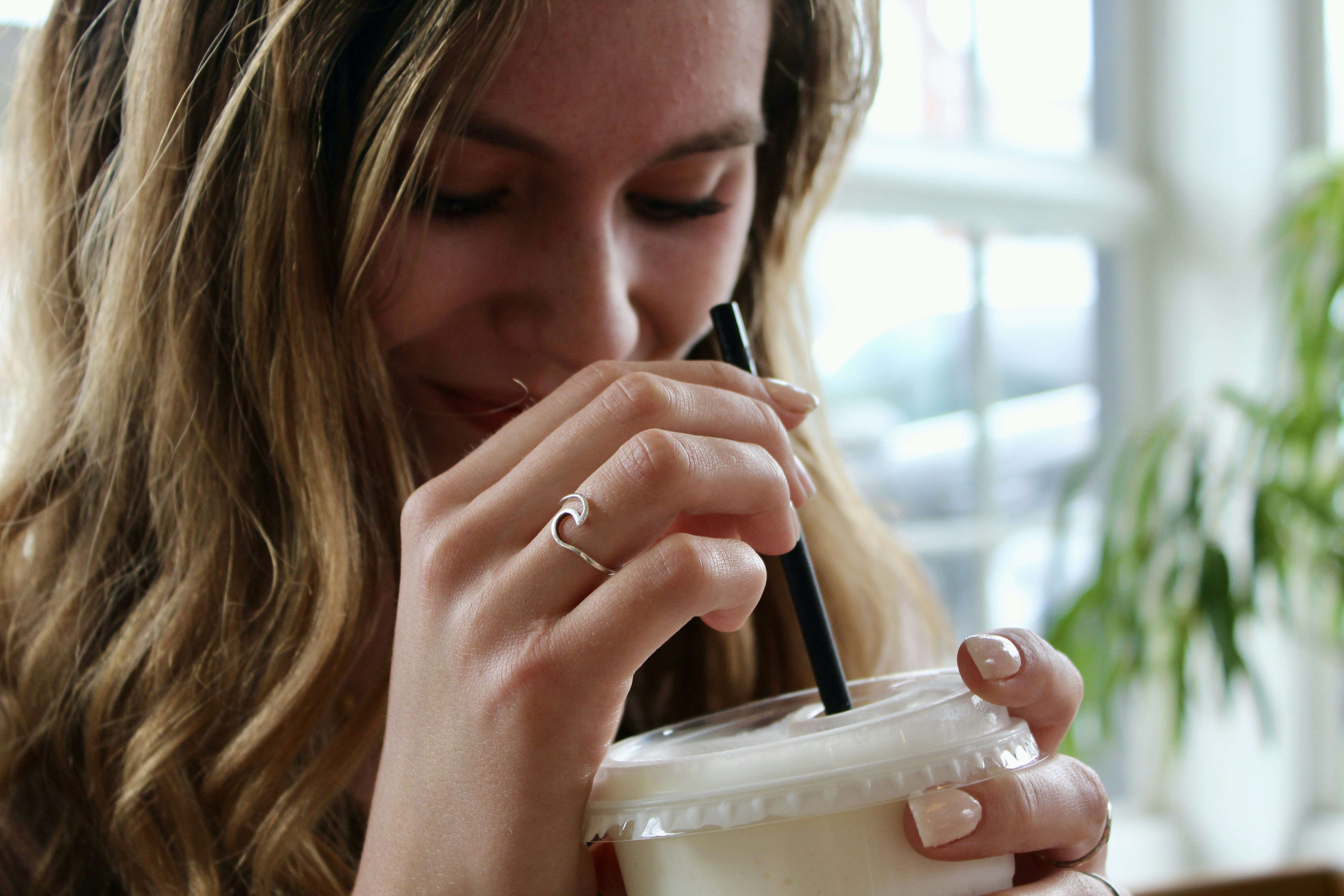 woman holding black pen and white plastic cup