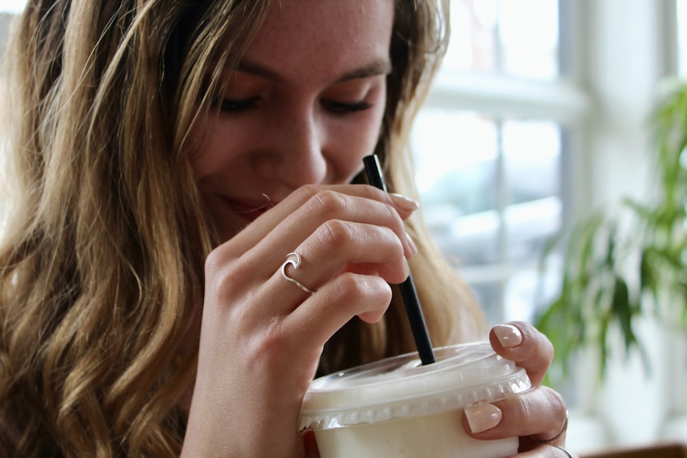 woman holding black pen and white plastic cup