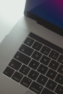 A close-up of hands typing on a laptop with a vibrant blue gradient background.