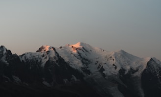 Sunrise over the snow-capped peaks of the Swiss Alps with soft golden light.