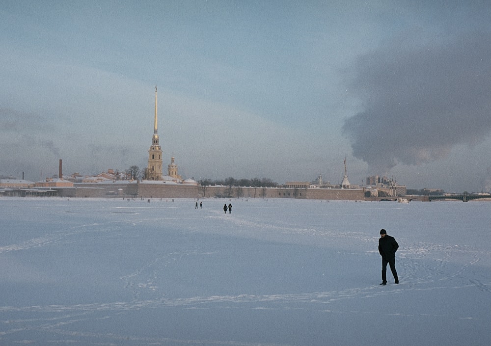 person in black jacket walking on snow covered field during daytime