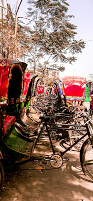 A row of sleek e-rickshaws powered by lithium-ion batteries parked under bright sunlight.