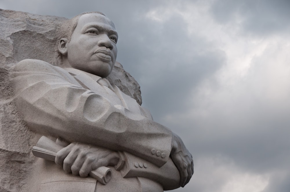 man statue under white clouds during daytime