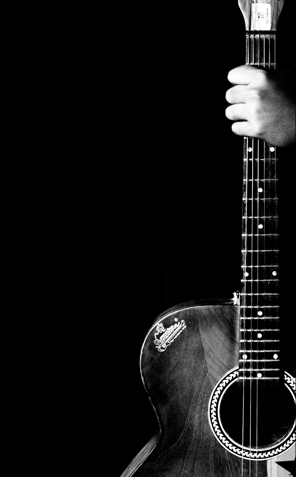 grayscale photo of man playing acoustic guitar