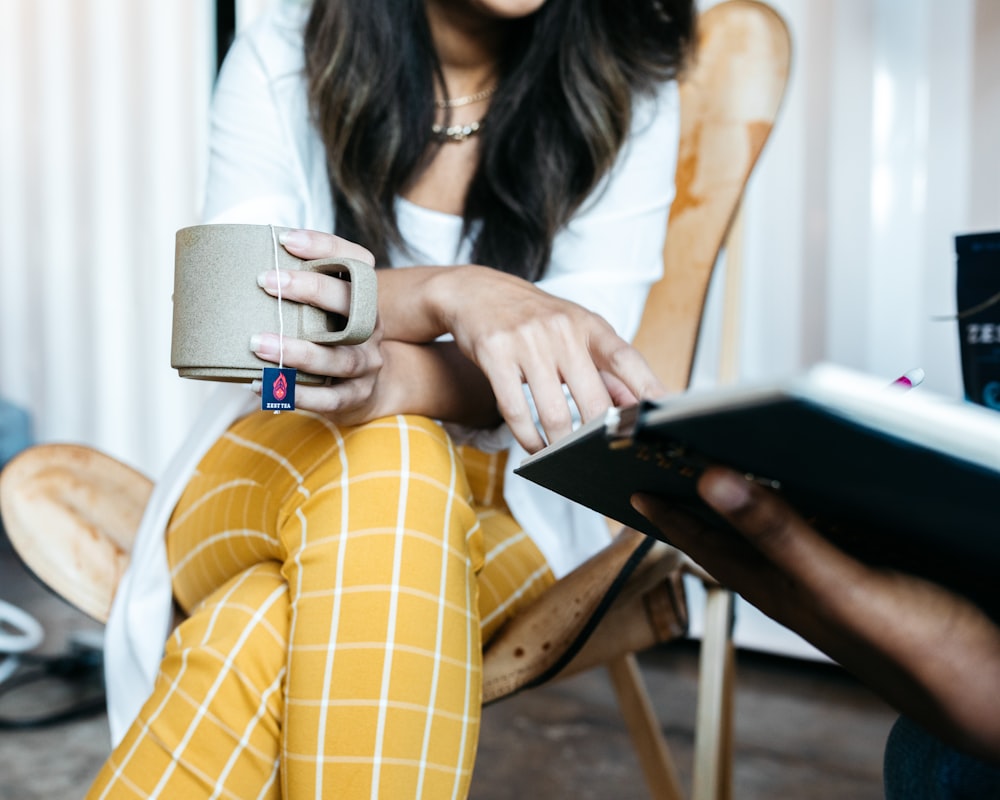 woman in white long sleeve shirt and yellow and white plaid pants sitting on chair