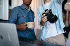 man in blue dress shirt holding black dslr camera