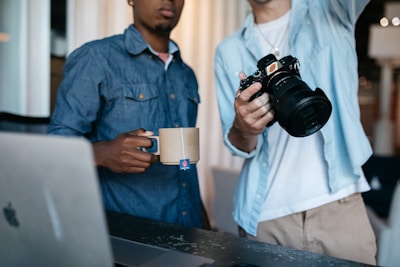 man in blue dress shirt holding black dslr camera