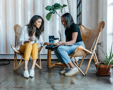 Two friends sharing a warm conversation over tea in a sunlit living room.