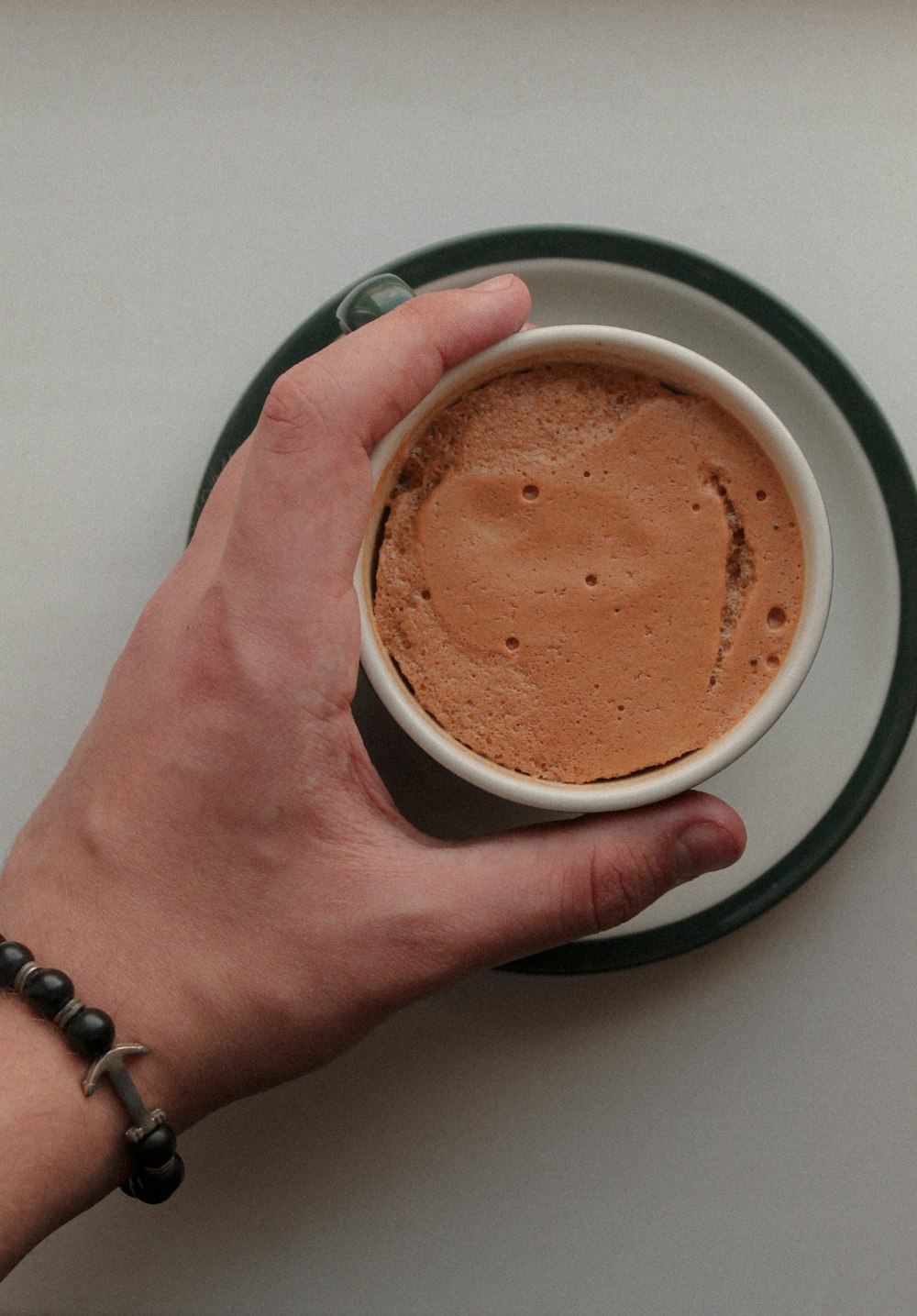 person holding white ceramic mug with brown liquid