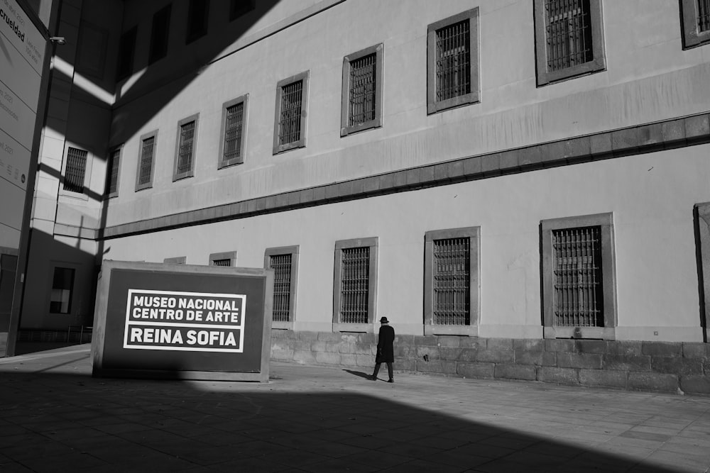 man in black jacket walking on sidewalk near white building during daytime