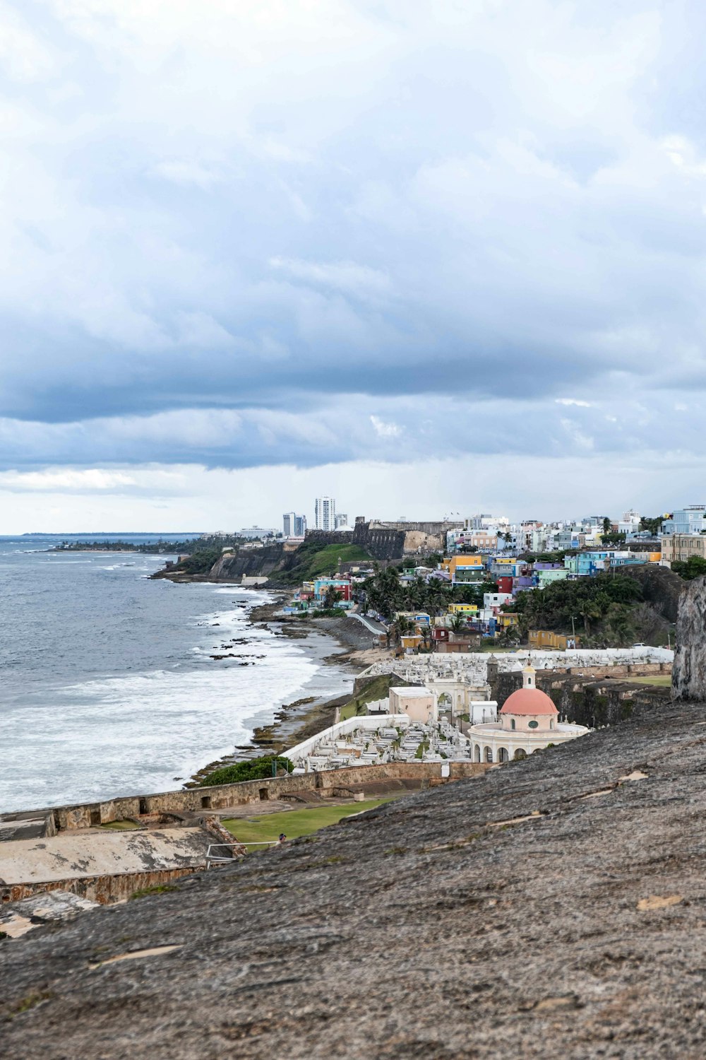 edifícios de concreto branco e marrom perto do mar sob nuvens brancas durante o dia