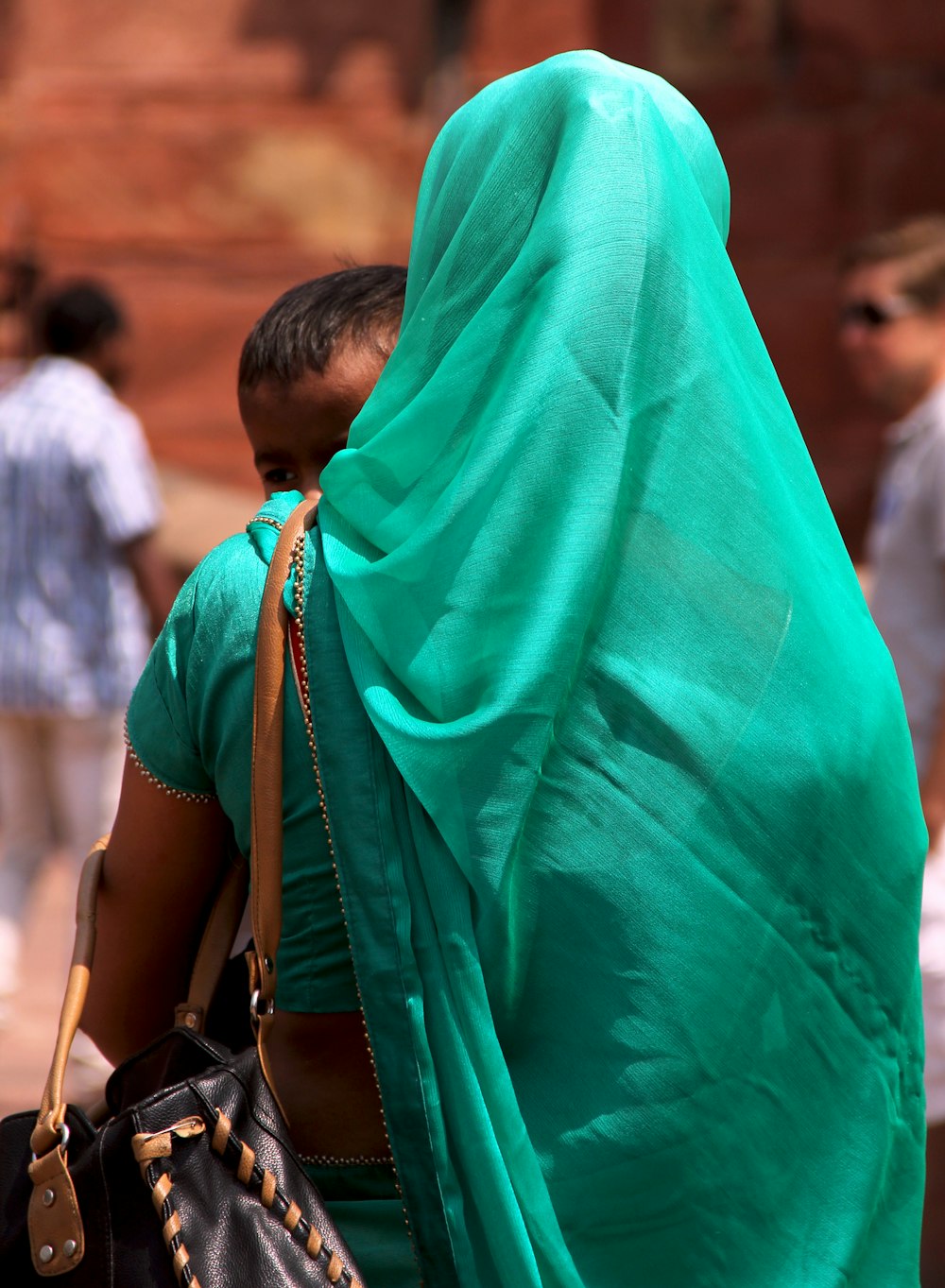 woman in teal hijab standing near people during daytime