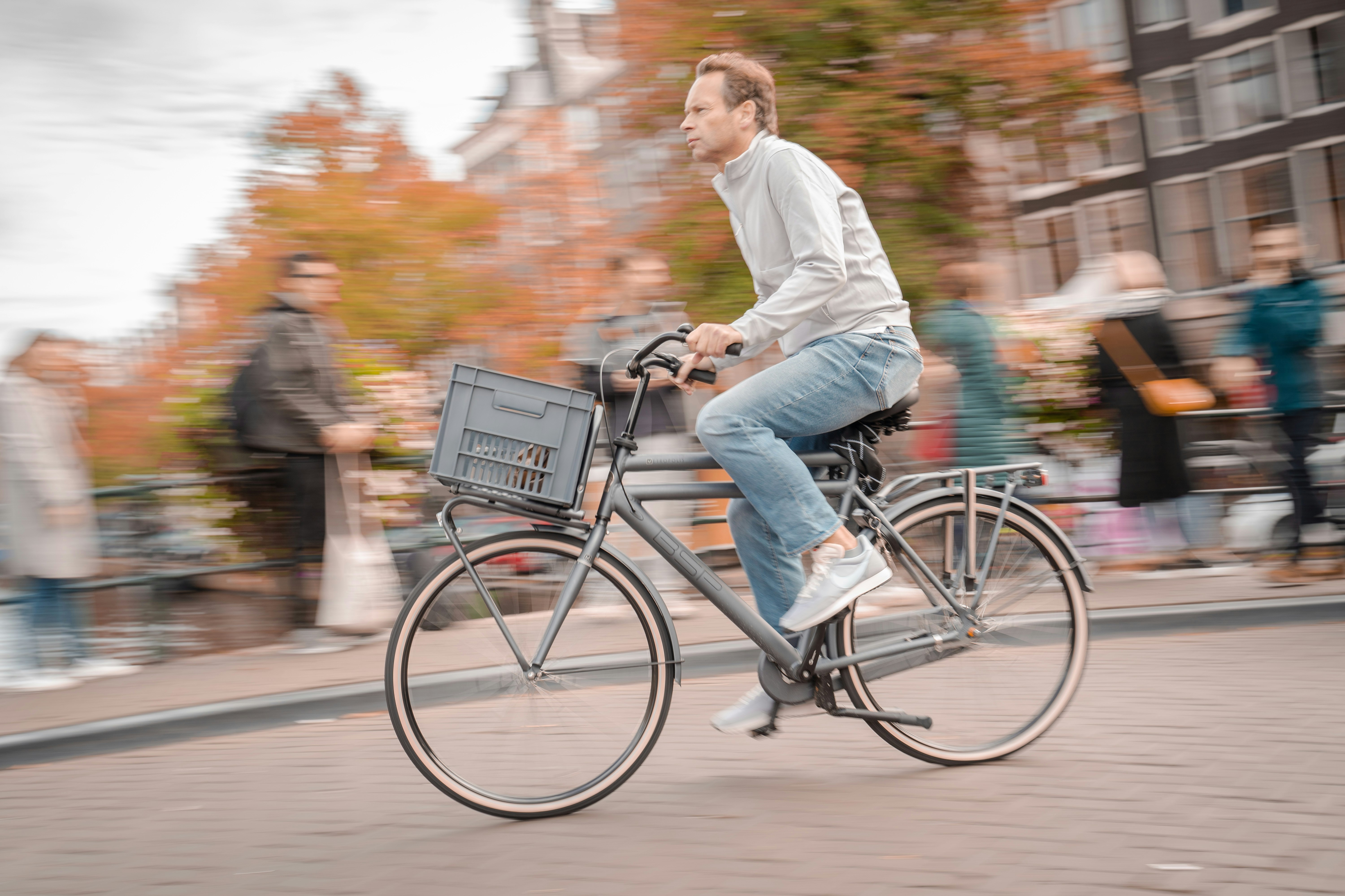 man in white dress shirt and blue denim jeans riding on black bicycle during daytime