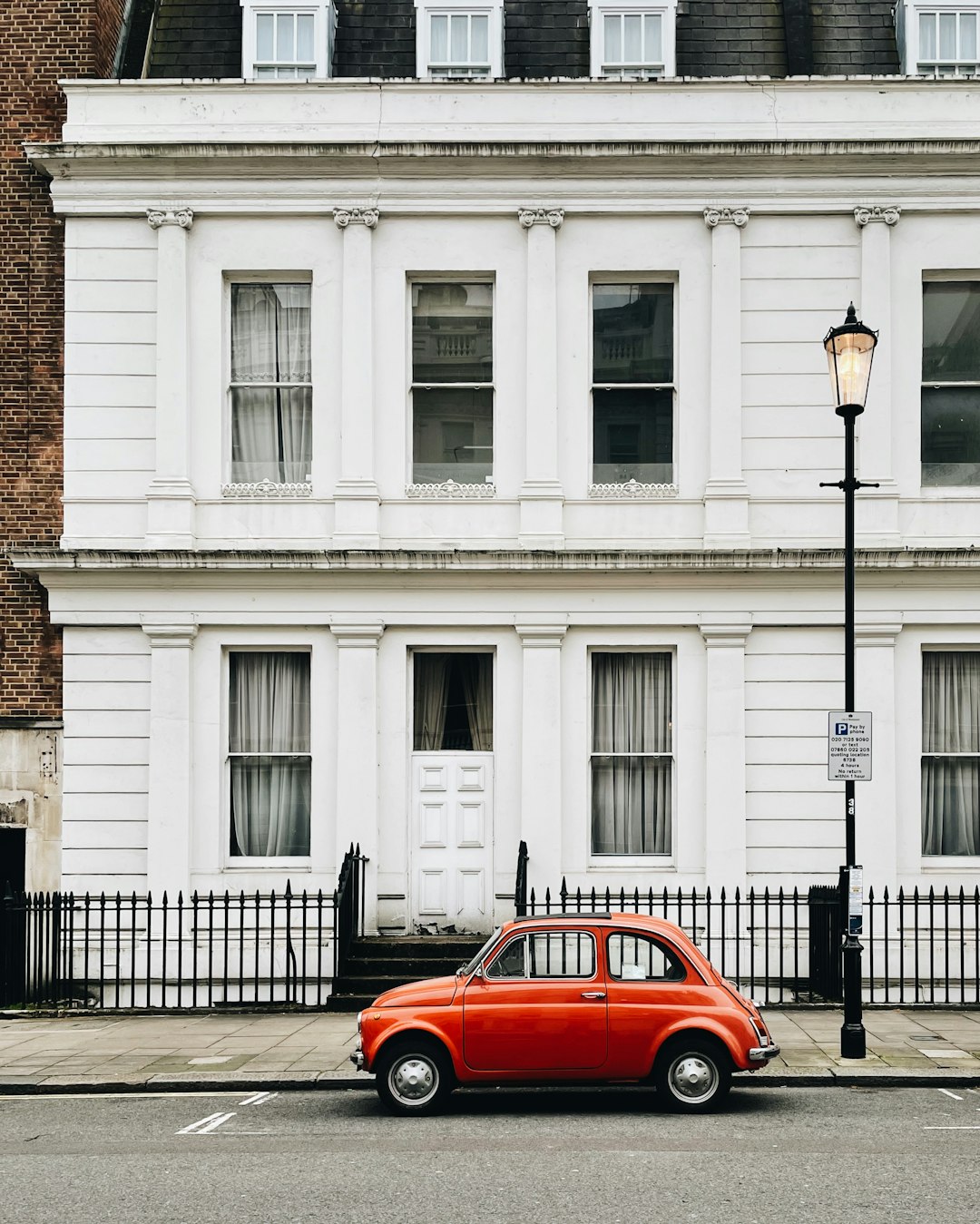 red car parked in front of white building