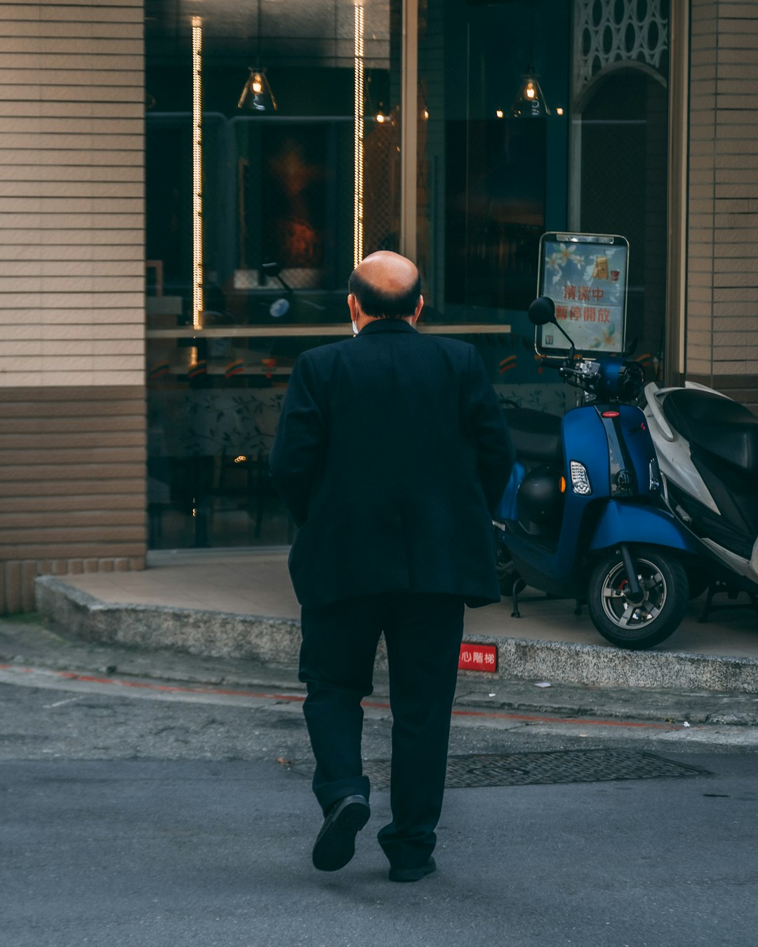 man in black coat standing beside blue and black motor scooter during daytime