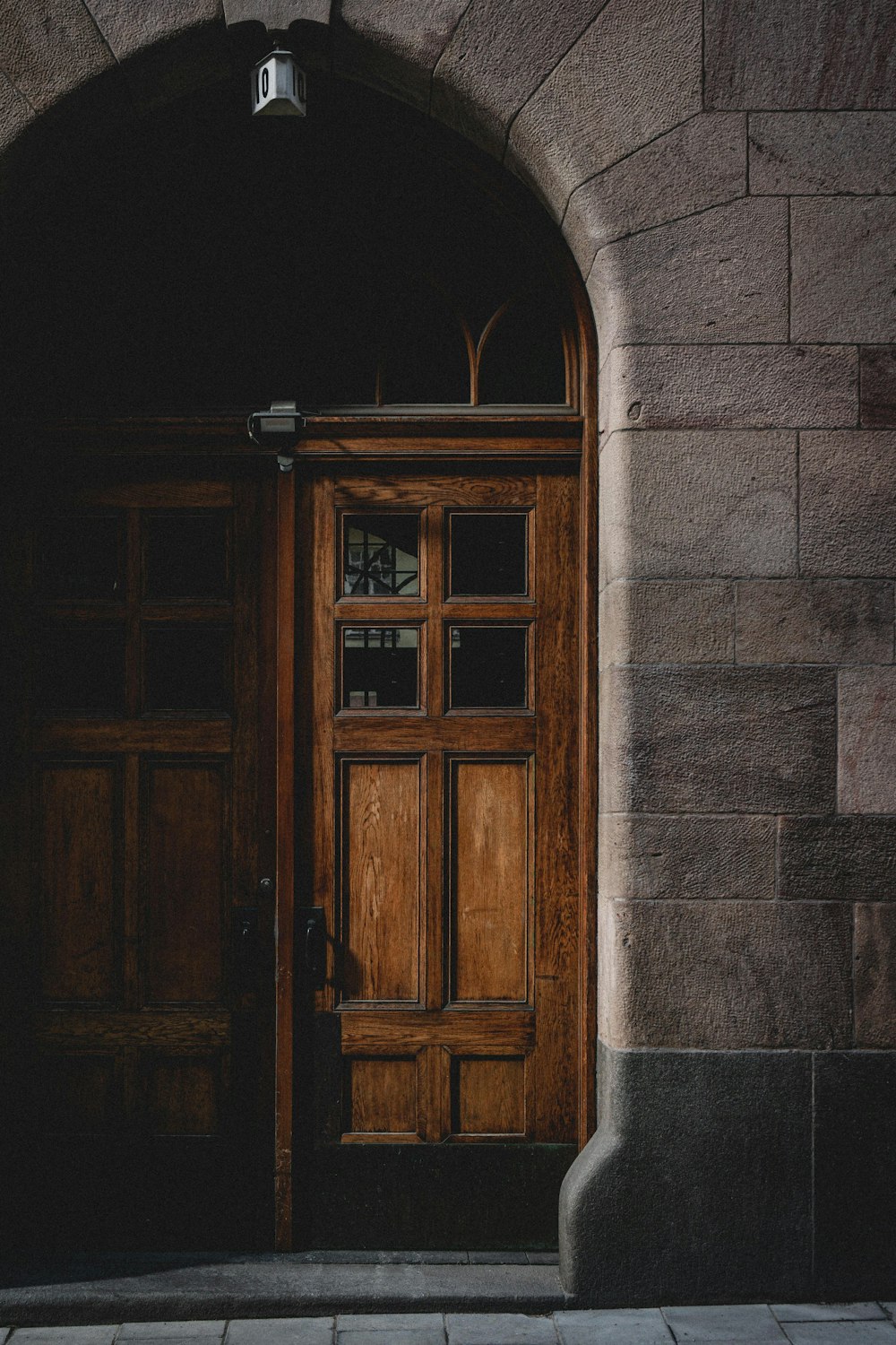 puerta de madera marrón sobre pared de hormigón gris