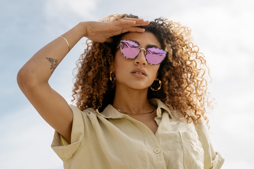 woman in white button up shirt wearing purple sunglasses