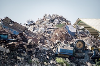 A close-up photo of various scrap metals including copper wires, aluminum sheets, and iron rods stacked together.