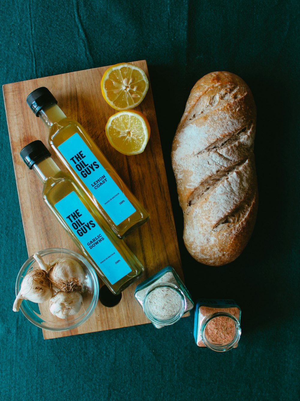 bread on brown wooden chopping board beside clear glass bottle