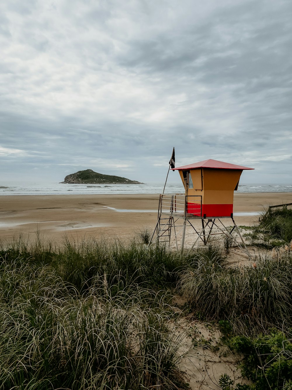 red and brown lifeguard tower on seashore during daytime