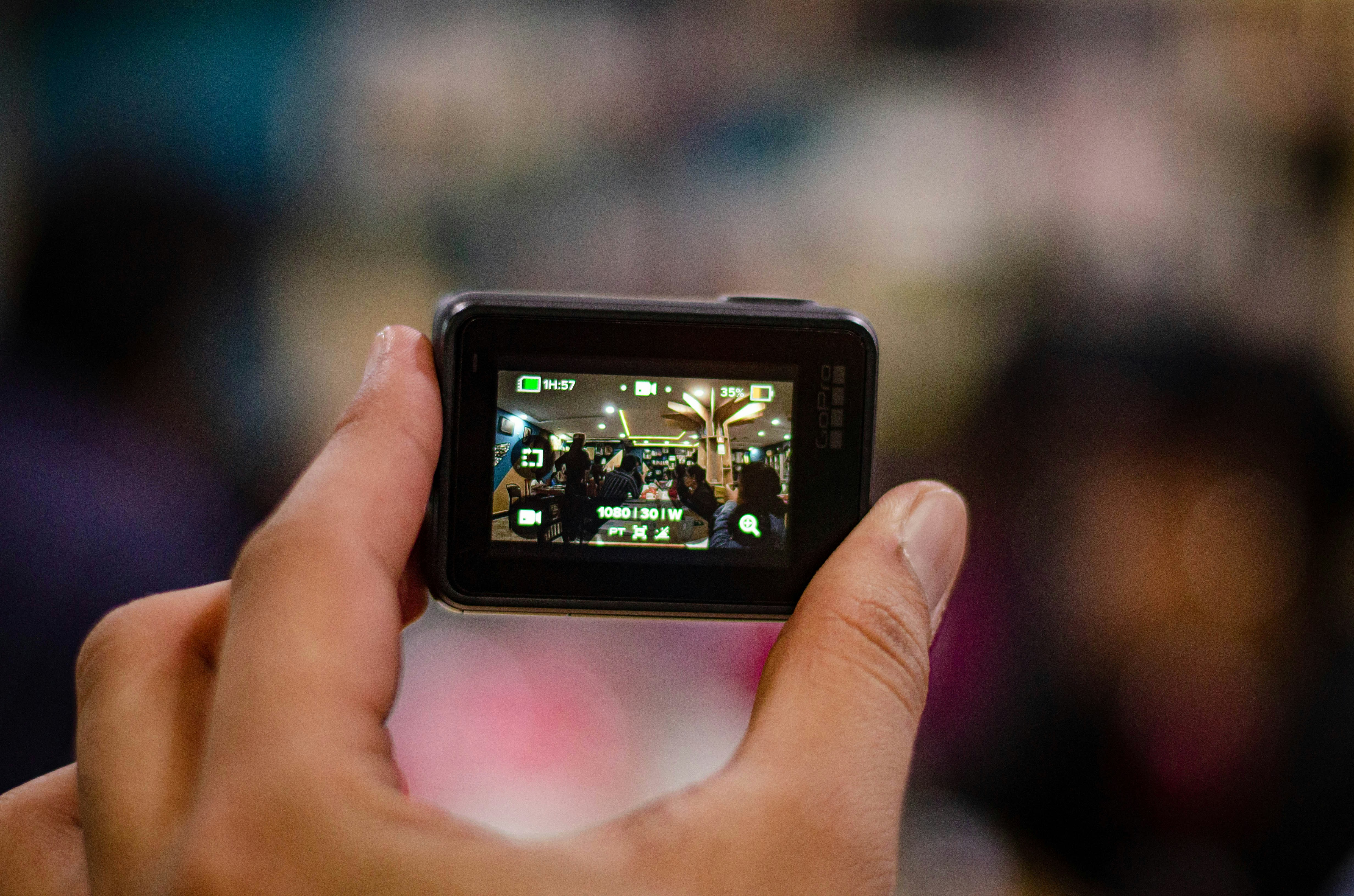  A person films and event, using a GoPro camera, the footage will later be enhanced with royalty free music and GoPro sound effects.