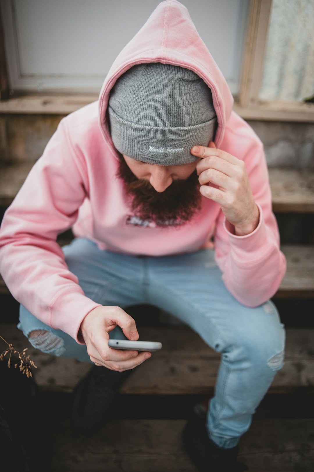 person in pink long sleeve shirt holding smartphone